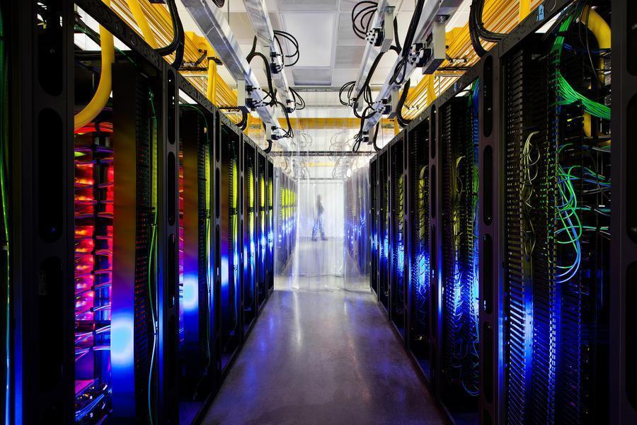 谷歌康瑟尔布拉夫斯数据中心中枢。图中是该数据中心的路由器和交换器。这个建筑内光纤网络的网速是普通家用连接速度的20万倍。光纤可以延着上方的黄色桥架布线。